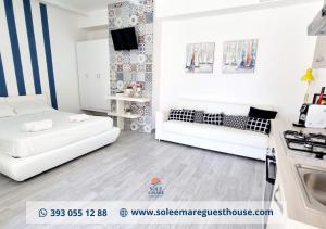 sala de estar con 2 sofás blancos y cocina en Sole E Mare, en Guardia Piemontese Terme