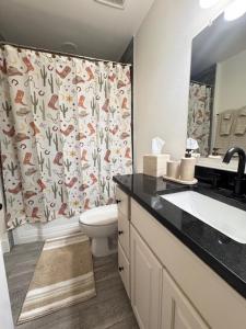 La salle de bains est pourvue d'un lavabo, de toilettes et d'un rideau de douche. dans l'établissement The Rodeo House - Near Rodeo Arena, à Mesquite 39 autres photos