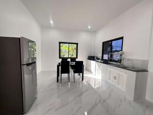 a kitchen with a table and chairs and a refrigerator at Grandma's Samui Garden - บ้านสวนคุณย่า in Ban Tai +14 photos