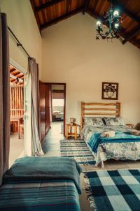 une chambre avec deux lits et un lustre dans l'établissement Pousada Recanto dos Pássaros, à Visconde de Mauá