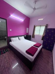 une chambre avec un grand lit aux murs violets dans l'établissement The Golden Seaview - Homestay, à Gokarna