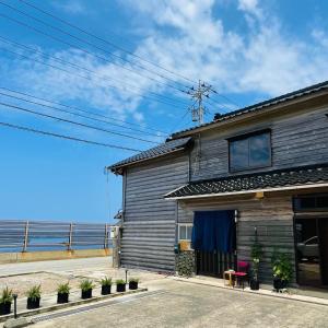 a house with the ocean in the background at 夕日が海に沈む宿 まひるのつき in Shika