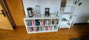 Neben einer Tür steht ein weißes Bücherregal voller Bücher. in der Unterkunft Anahata Lodge, Alojamiento Tranquilo en Medio de la Naturaleza in Puerto Varas
