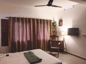 科钦G Hotels And Resorts的一间卧室配有一张床、一台电视和一把椅子