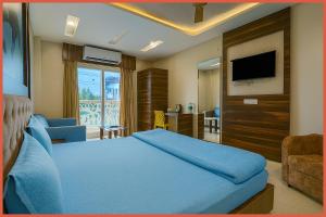 普里BALCONY ROOMS Hotel PREMIUM RR RESIDENCY Near Jagannath Temple - Sea Beach 5 minute walking distance - Bangali Market- Lift-Parking And Restaurant Facilities -Prime Location - Fully Air Conditioning Luxuary Rooms - Top Rated Hotel In Puri的卧室里有一张蓝色的床和一台电视