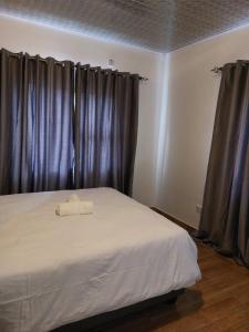 a bedroom with a white bed with purple curtains at Mandy & Mos' Greenfields Cottage in Gaborone