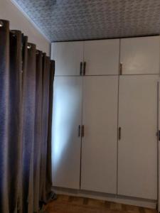 a room with white cabinets and a curtain at Mandy & Mos' Greenfields Cottage in Gaborone +2 photos