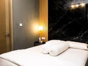 香港1 BD AT Coastal Skyline的一张带白色枕头和黑色墙壁的床