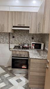 une cuisine avec une cuisinière et un micro-ondes dans l'établissement Résidence El Boustane, à Skikda
