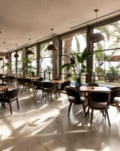 a restaurant with tables and chairs and large windows at Iliria Internacional Hotel in Durrës