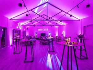 纳斯voco The Club - Dublin Gateway by IHG的粉红色房间里有桌椅的房间