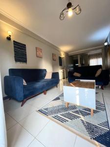 a living room with two blue couches and a table at Carihaven Homz Najjera in Buwate +1 photo