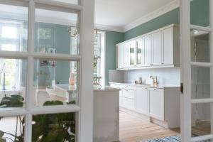 a kitchen with white cabinets and green walls at Lindegaarden Kollund in Kruså +72 photos