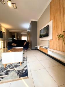 a living room with a couch and a tv on a wall at Carihaven Homz Najjera in Buwate