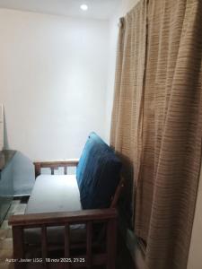 Ein Bett mit einem blauen Kissen steht neben einem Vorhang. in der Unterkunft Departamento Bellas Artes Planta Alta in Irapuato