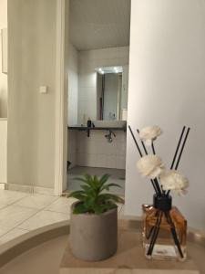 une salle de bain avec un vase avec des fleurs sur une table dans l'établissement Stefani retro luxury apartments, à Chalcis
