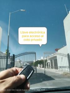 Eine Hand, die vor einem Zaun ein Handy hält. in der Unterkunft Departamento Bellas Artes Planta Alta in Irapuato