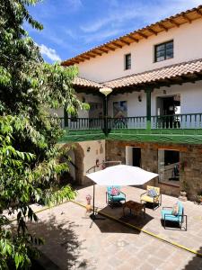 Un patio frente a una casa con una sombrilla blanca. en Usgar San Pedro Boutique, en Cusco