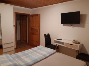 a bedroom with a bed and a desk and a television at Ferienhaus Würzgarte in Ürzig