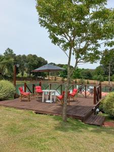 eine Holzterrasse mit Stühlen, einem Tisch und einem Sonnenschirm in der Unterkunft Palast Haus Pousada in Gramado + 88 Fotos