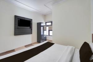 um quarto com uma cama e uma TV na parede em Hotel O KK em Haldwani-cum-Kathgodam