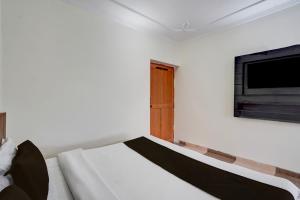 um quarto com uma cama e uma TV na parede em Hotel O KK em Haldwani-cum-Kathgodam mais 16 fotografias