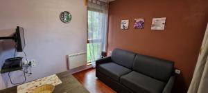 a living room with a black couch and a window at LE HAMEAU du COMTE de FOIX in Mercus-Garrabet