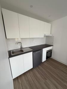 an empty kitchen with white cabinets and a sink at Studio neuf à Crosne in Crosne