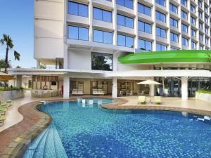 a hotel with a large swimming pool in front of a building at Ibis Styles Bogor Raya in Bogor