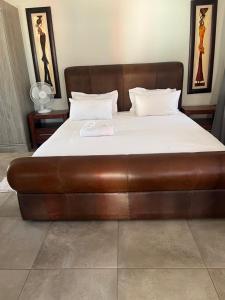 a large bed with a brown leather foot board at Florencepalms resort & Spa in Marble Hall
