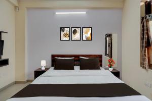 - une chambre avec un grand lit et trois photos sur le mur dans l'établissement Hotel O Jagatpura Central Railway Station Jaipur, à Jaipur