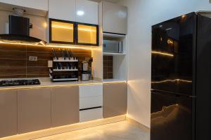 AjaElysian shores suites - BRADFORD的厨房配有白色橱柜和黑色冰箱 更多6张照片