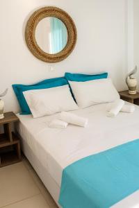 ein Bett mit blauen und weißen Kissen und einem Spiegel in der Unterkunft Erifili's Apartments in Skala