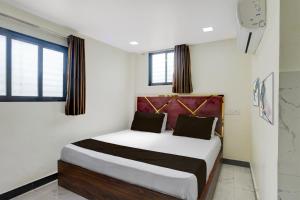 Schlafzimmer mit einem Bett mit weißen Wänden und Fenstern in der Unterkunft Hotel O Jagruti Nagar Ghatkopar Formerly Icy Cool in Mumbai
