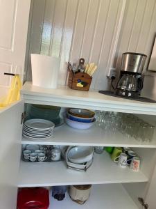 a white shelf with plates and dishes on it at Morada Tito Georgi in Gramado