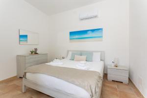 um quarto branco com uma cama e duas mesas de cabeceira em Costa Ovest Apartment 2 em Nurachi