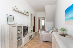 uma sala de estar com um sofá e uma TV em Costa Ovest Apartment 2 em Nurachi