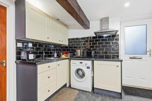 a kitchen with a washing machine and a washer at The Snug- Ideal for Work & Leisure Stays in Bury