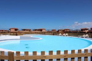 a large swimming pool with chairs and a fence at Villa Majanicho Outside con piscina in Majanicho