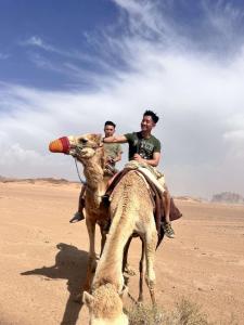 two men riding on a camel in the desert at Abdo waid rum in Aqaba