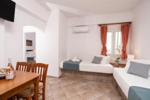 a room with two beds and a table and a desk at Cyclades Beach Apartments in Platis Gialos