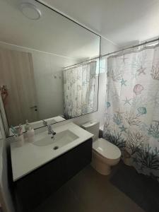 ein Badezimmer mit Waschbecken, Toilette und Spiegel in der Unterkunft Departamento completo in Iquique