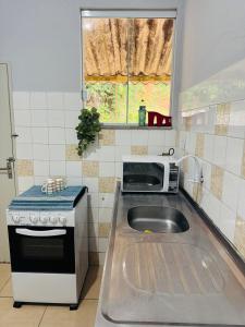 une cuisine avec un évier et un micro-ondes dans l'établissement Casa próxima ao centro a 3 min de carro, à São Lourenço