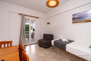 a bedroom with a bed and a chair and a table at Cyclades Beach Apartments in Platis Gialos