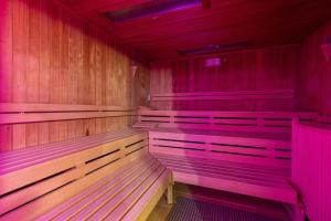 an empty sauna with wooden benches and pink lighting at IFA Rügen Hotel & Ferienpark in Binz