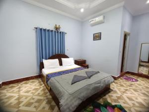 a bedroom with a bed and a blue curtain at Good Day Kampot Guesthouse in Kampot