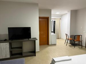 Una sala de estar con un televisor y una mesa con sillas. en Rooftop Gallery Hostel, en Tirana