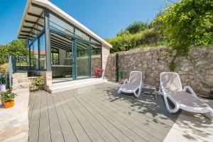 deux chaises assises sur une terrasse devant une maison dans l'établissement Ferienhaus Für 5 Personen Ca 218 M Sup2 In Podgora, Dalmatien Gespanschaft Split Dalmatien, à Podgora