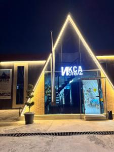 a building with a sign that reads visa museum at night at ИксаОтель in Shymkent