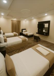a hotel room with three beds and a flat screen tv at فندق التاج ثلاثة مكة in Mecca